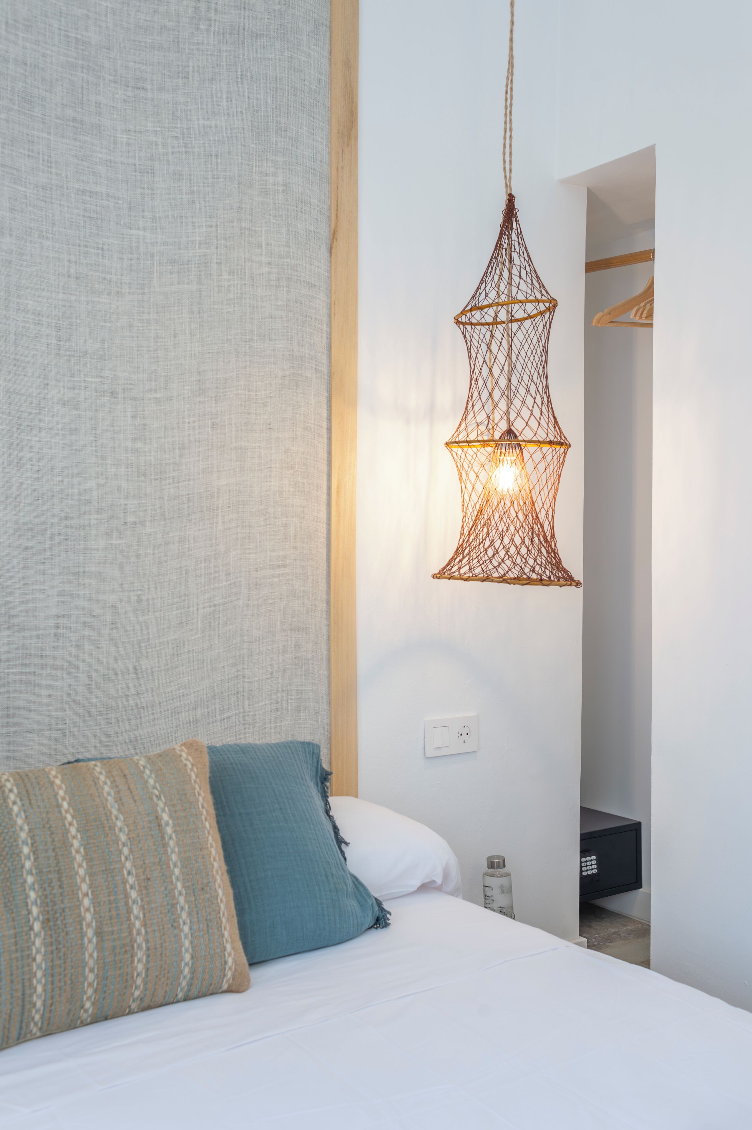 A bedroom with a bed, a hanging light fixture, and a wardrobe.