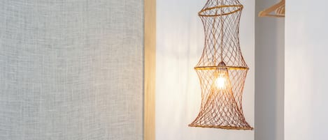 A bedroom with a bed, a hanging light fixture, and a wardrobe.