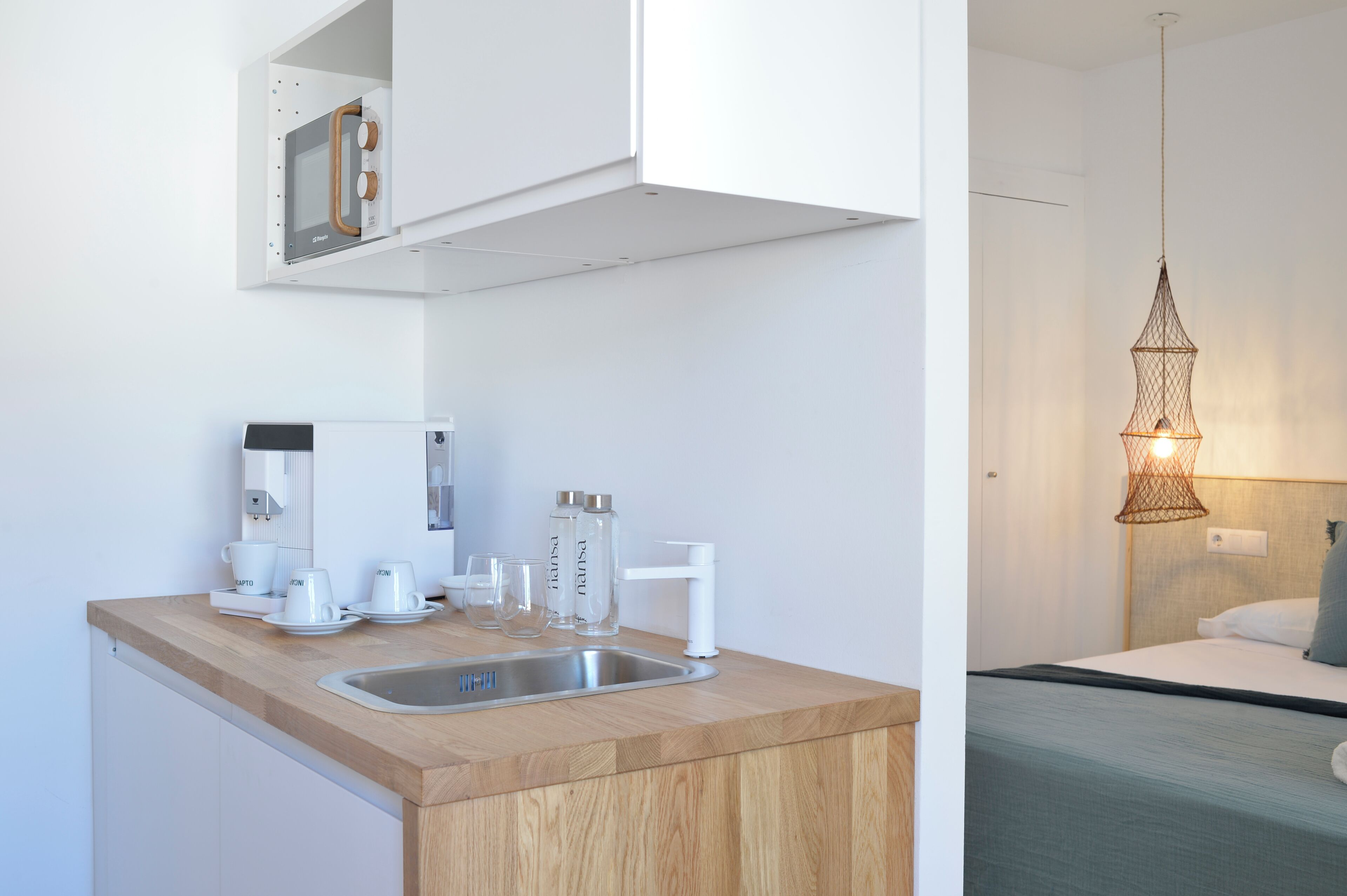 Una cocina moderna con encimera de madera, pileta de acero inoxidable y muebles altos blancos.