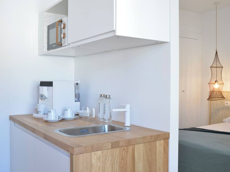 Una cocina moderna con encimera de madera, pileta de acero inoxidable y muebles altos blancos.