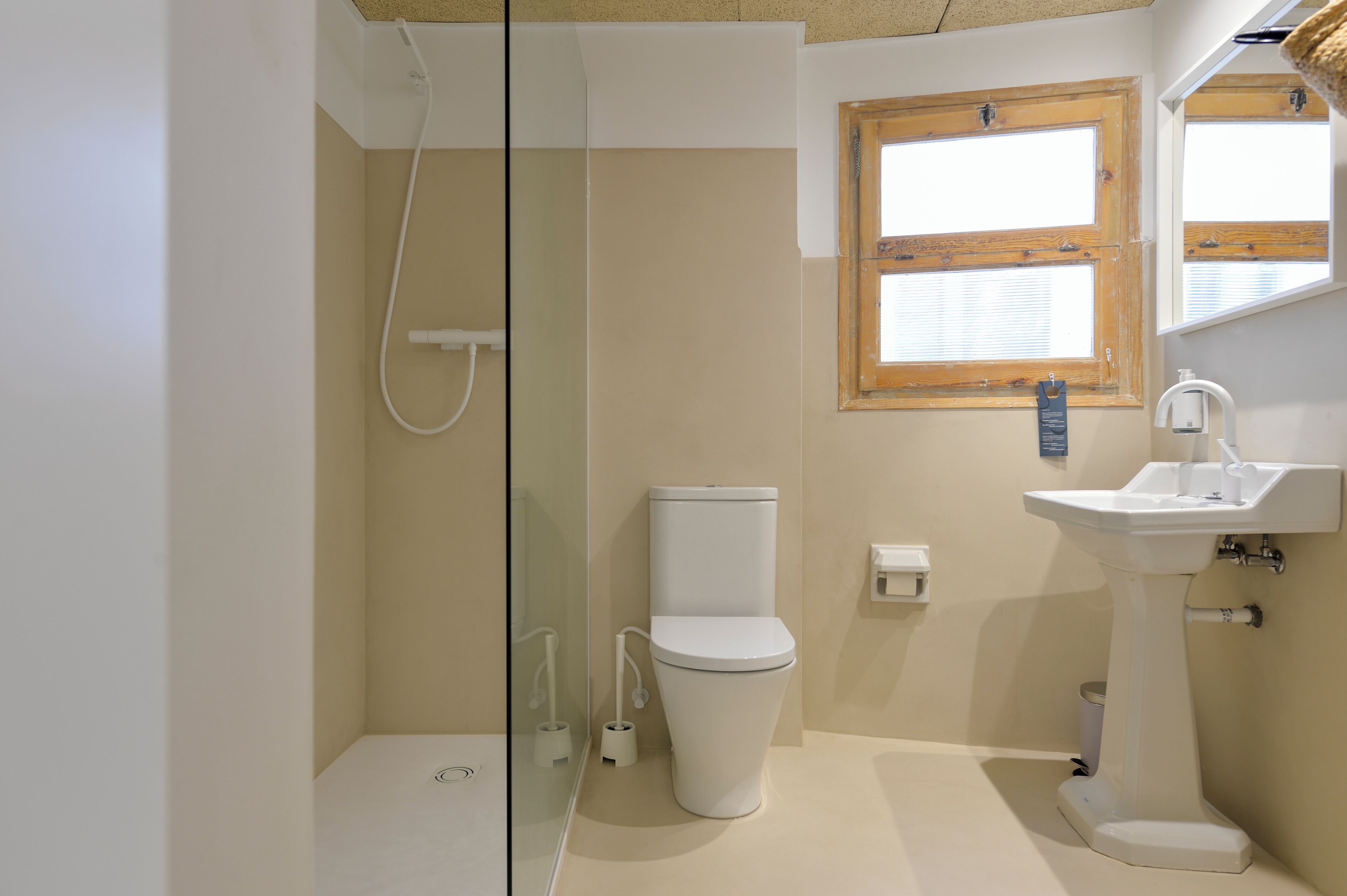 A bathroom with a glass shower enclosure, a toilet, and a sink.