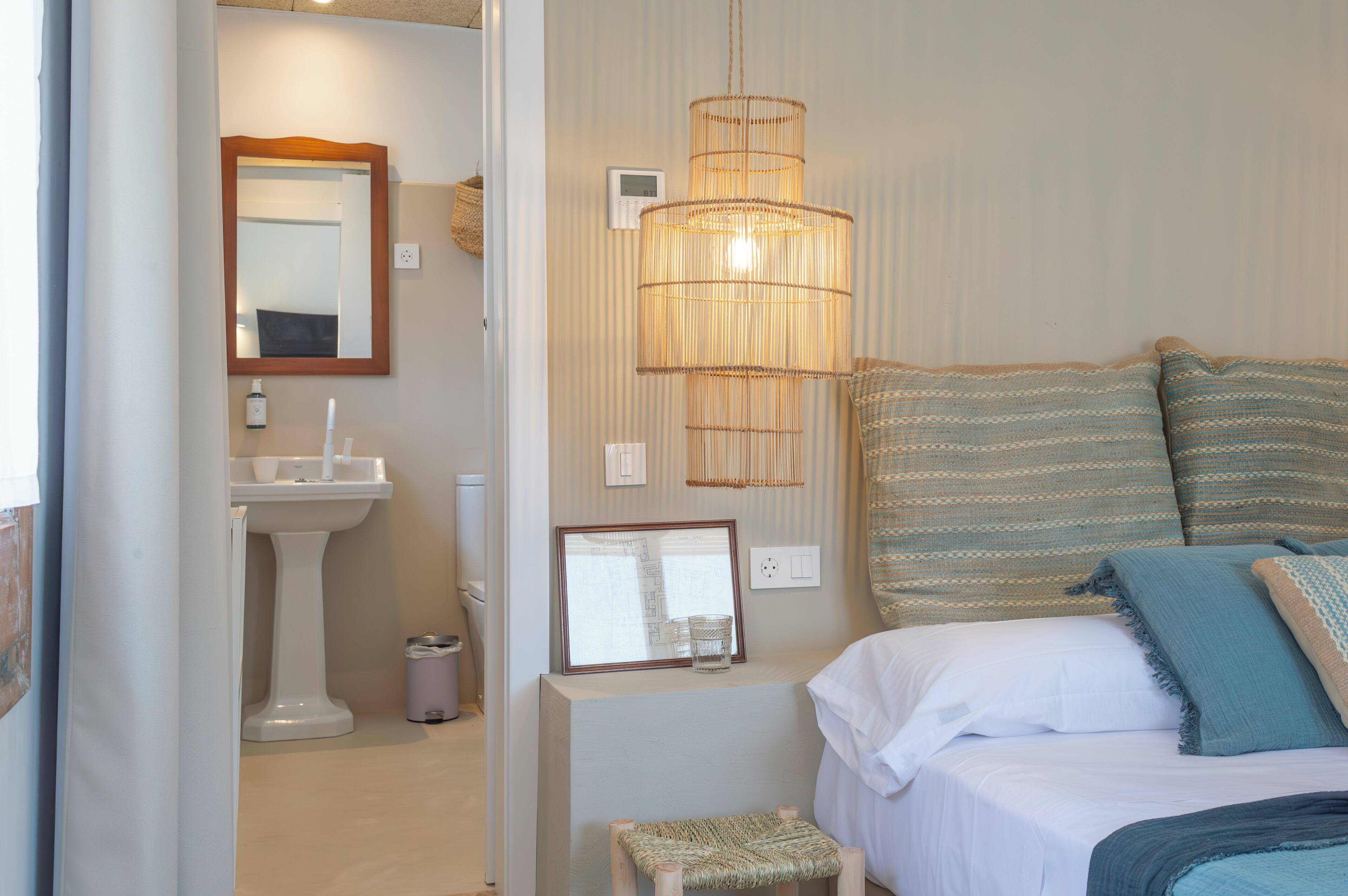 Un dormitorio con cama, mesita de noche y lámpara colgante.
