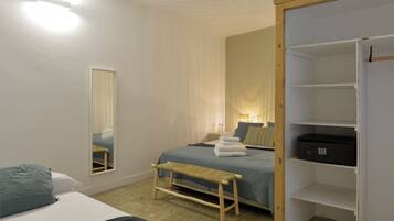 A bedroom with a bed, a bench, a mirror, a bedside table, and a wardrobe.