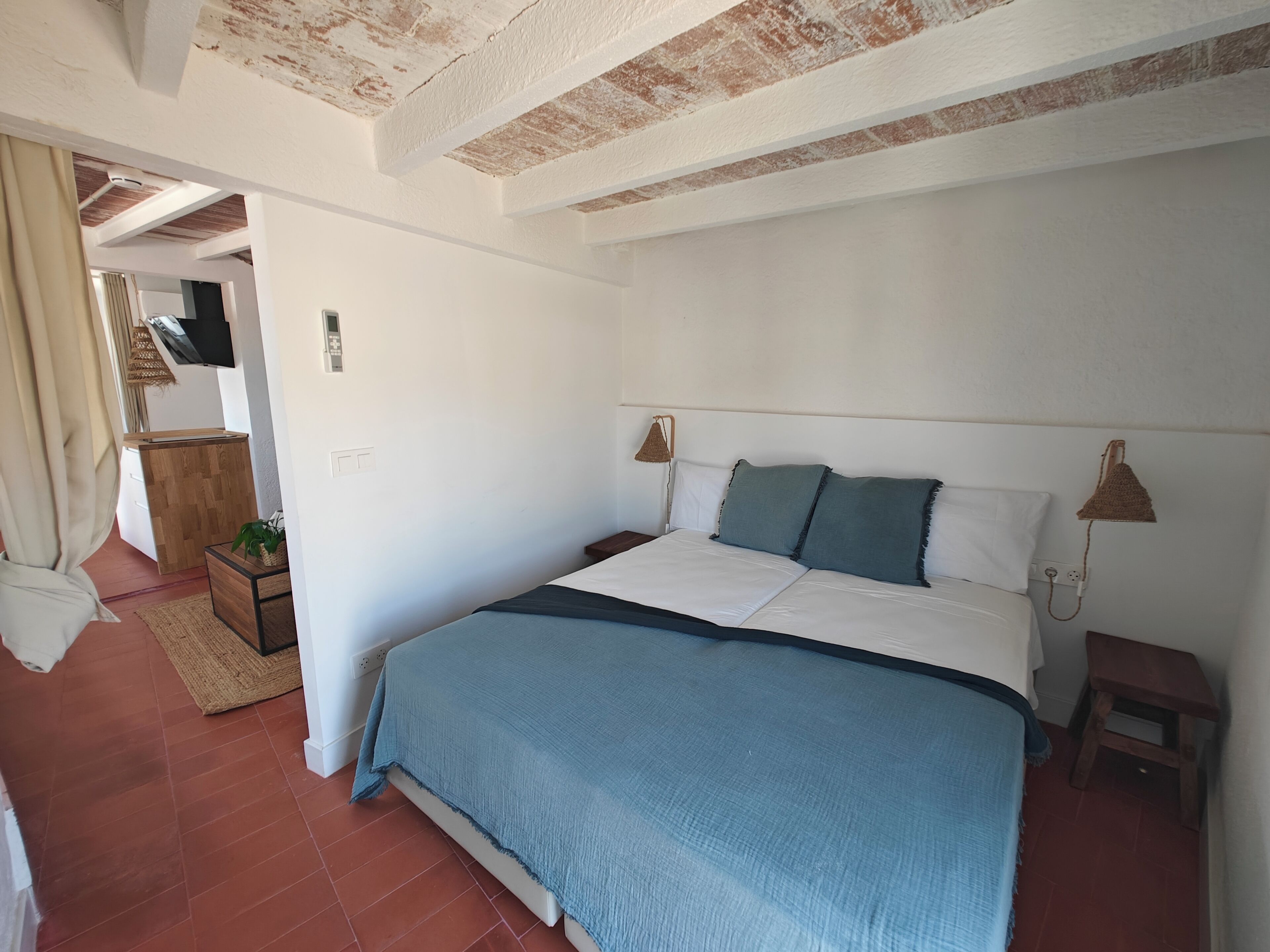 A bedroom with a bed, bedside tables, a TV, and a small wooden stool.