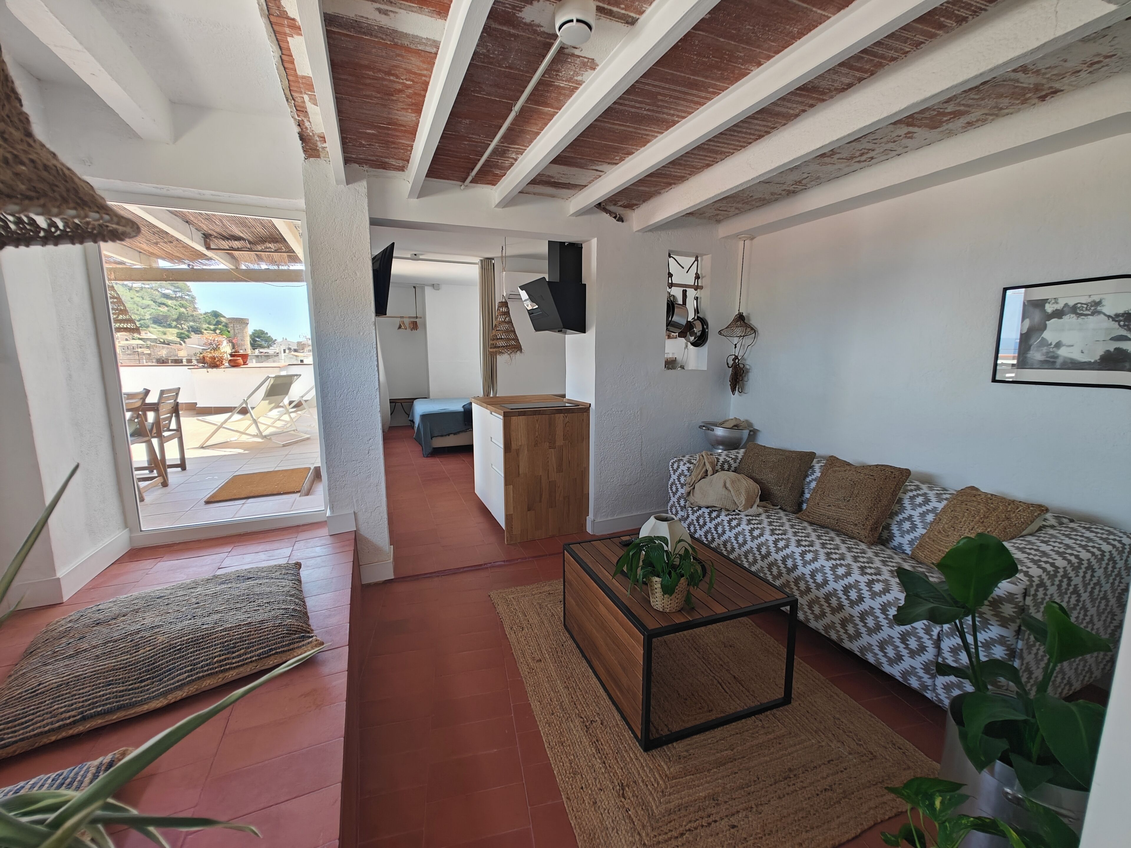Una sala de estar con un sofá, una mesa de centro, un televisor y una zona de cocina.