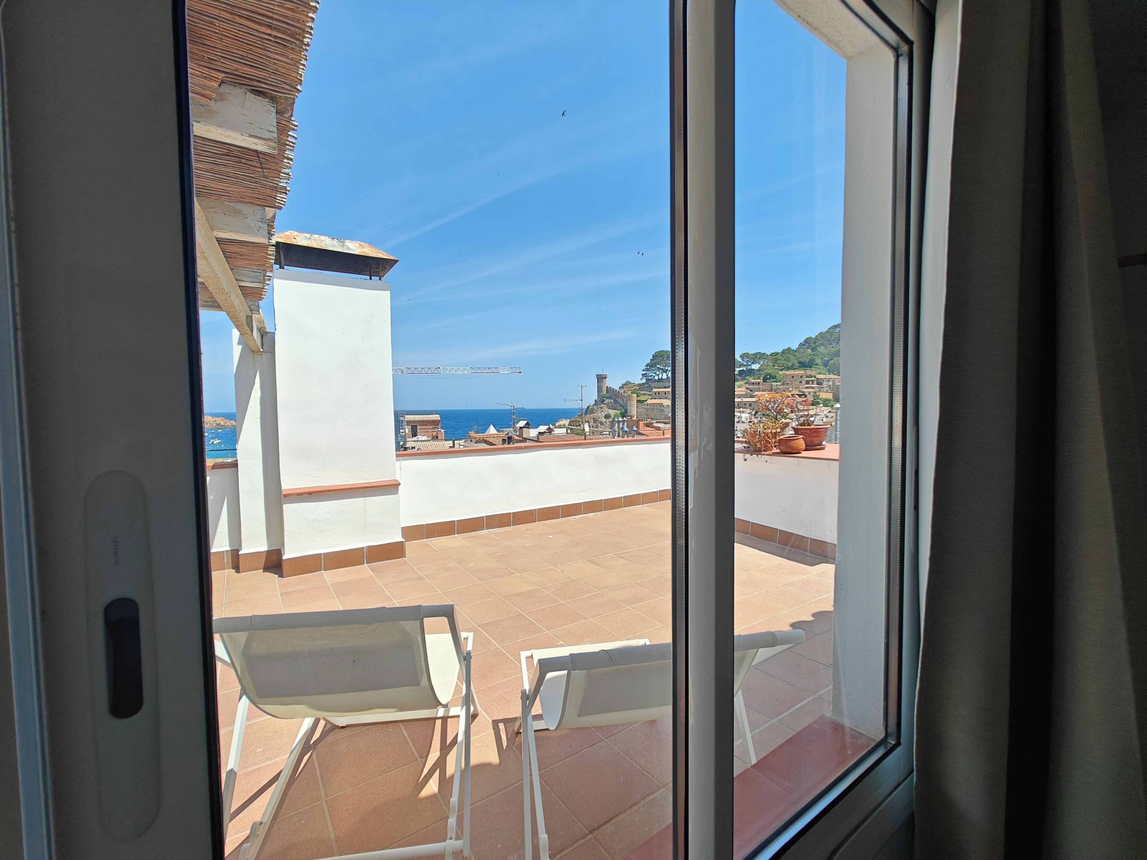 Een balkon met uitzicht op zee, een wit gebouw en een betegelde vloer.