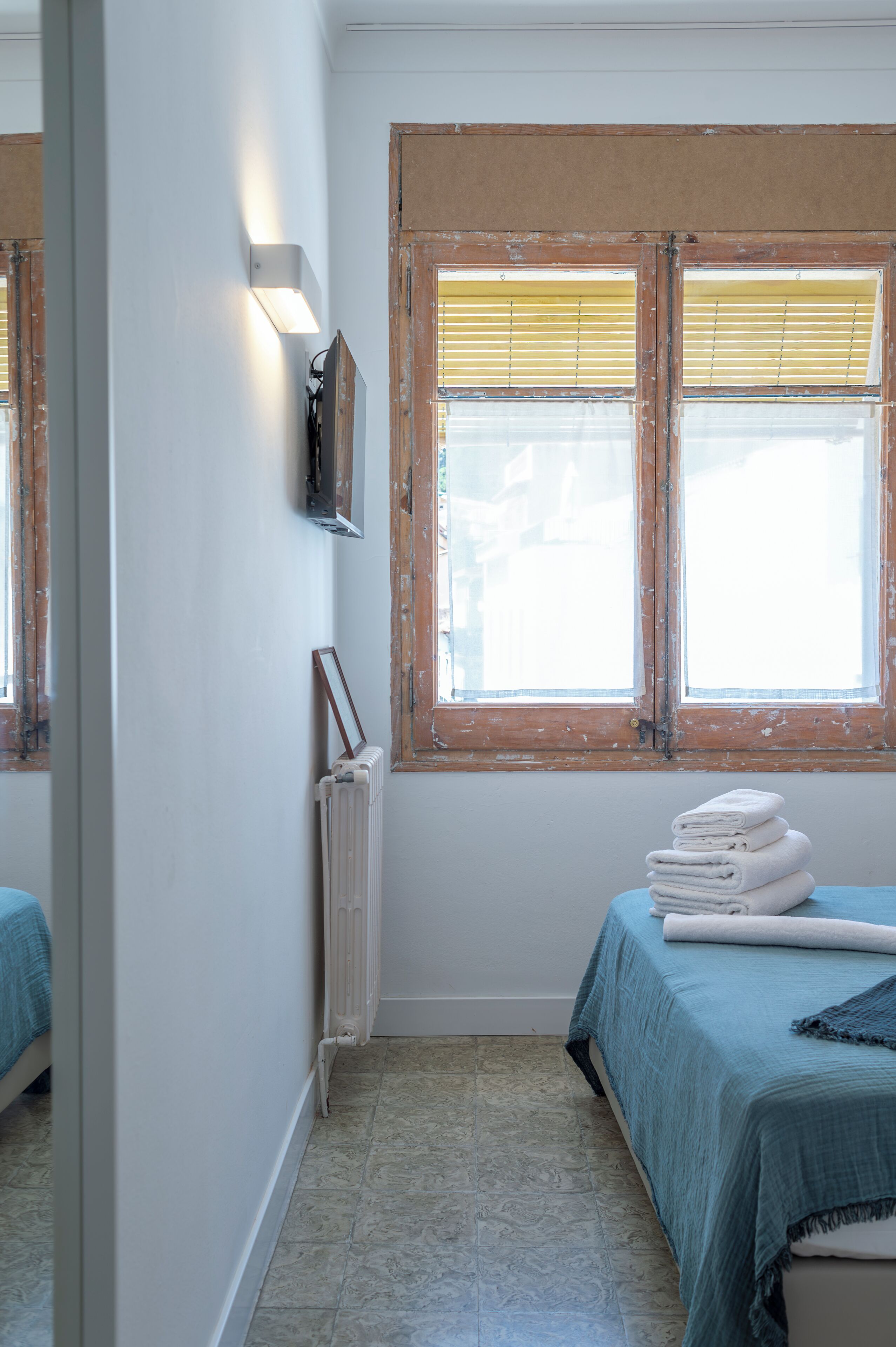 Habitación con dos camas, un radiador y una ventana con persianas.