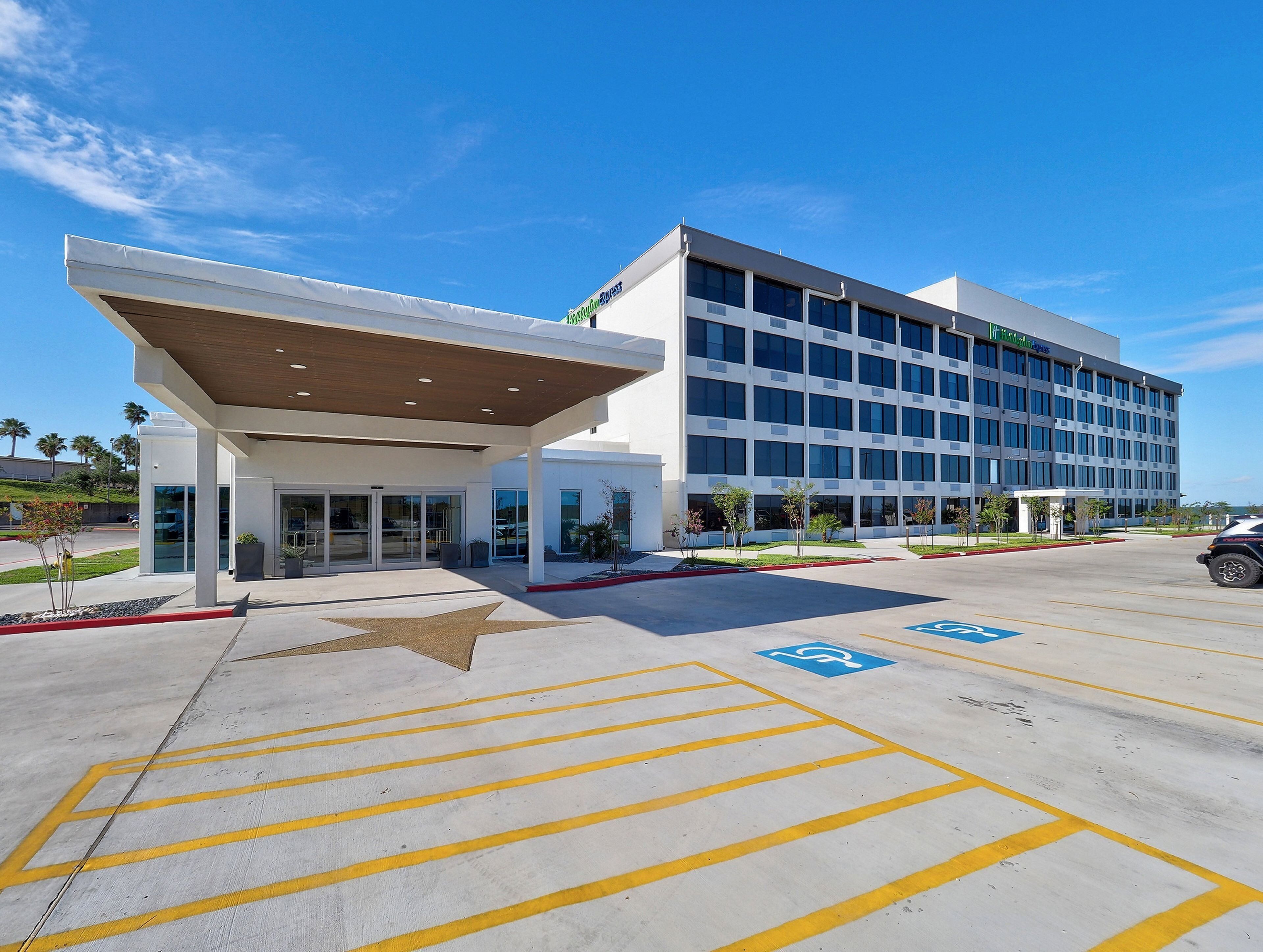 A modern hotel with a covered entrance and a parking lot with handicapped parking spaces.