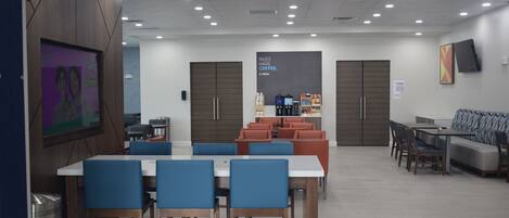 A modern dining area with tables and chairs, a coffee station, and a seating area with sofas and chairs.