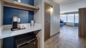 A modern hotel room with a coffee machine, a mini-fridge, and a small trash bin. - Holiday Inn Express Corpus Christi – Beachfront by IHG (Corpus Christi)