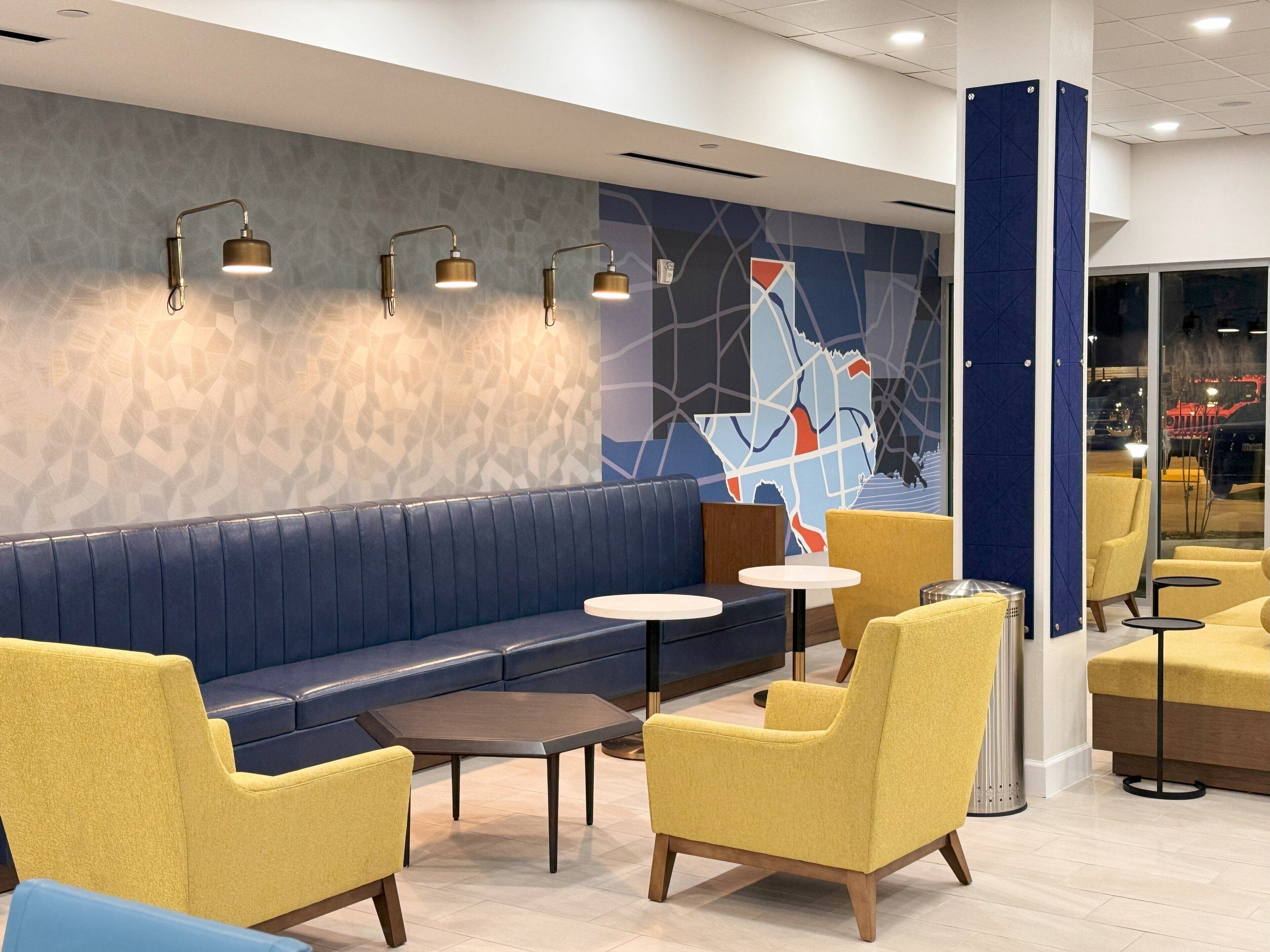 A modern lounge area with a blue sofa, yellow armchairs, and a small table.