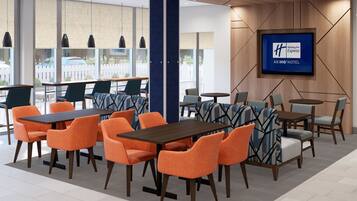 A hotel lobby with modern furniture, a large TV screen, and a view of the outside.
