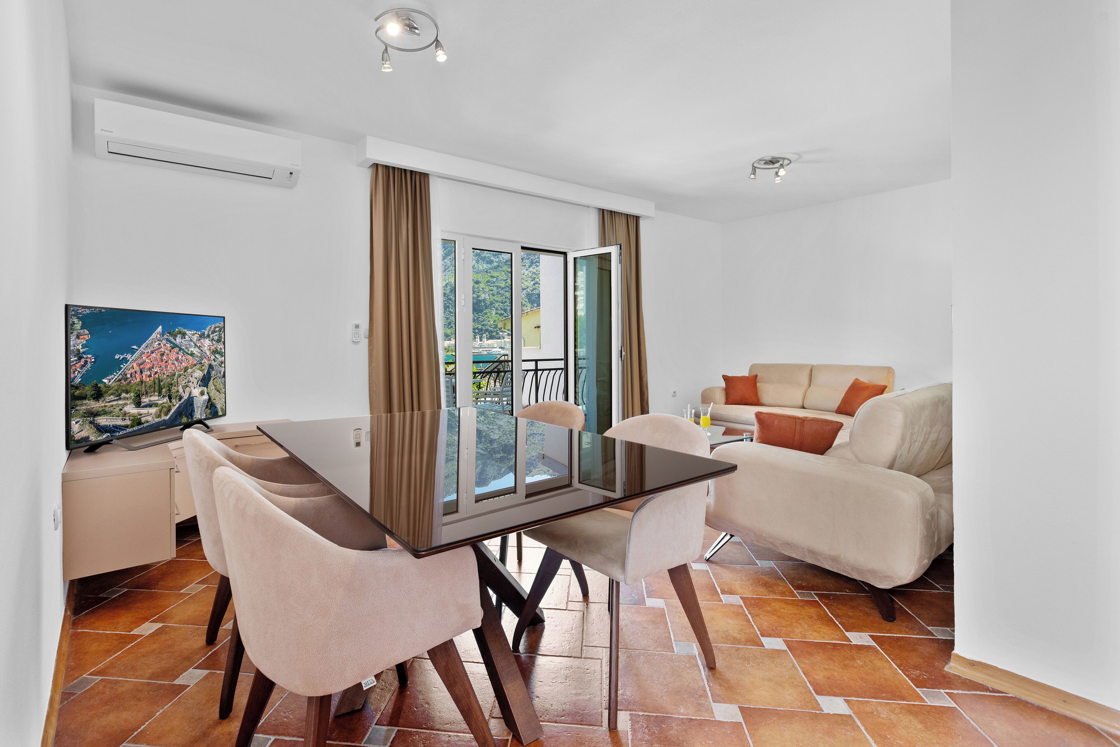 A modern living room with a dining area, a sofa, and a TV.