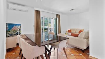 A modern living room with a dining area, a sofa, and a TV.