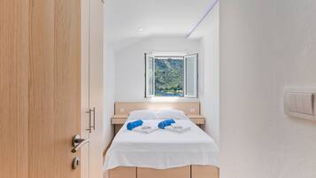 A modern bedroom with a bed, a window, and a wooden door.