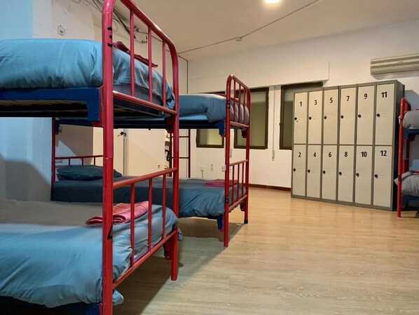 A dormitory room with bunk beds, a wardrobe with numbered lockers, and a wooden floor. - Boga Hostel (Madrid)