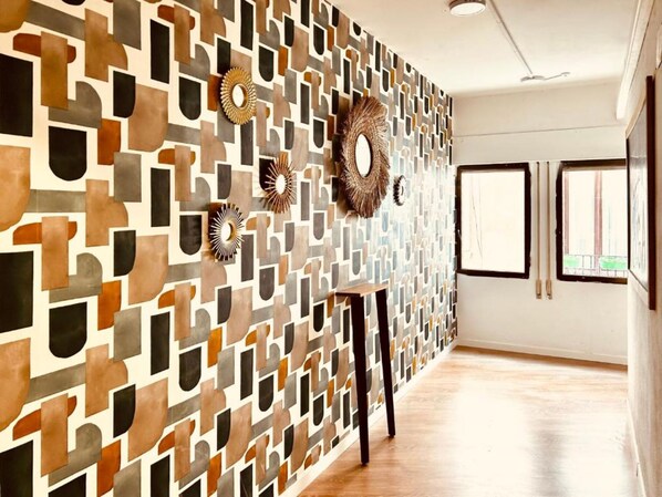 A modern room with a geometric patterned wall, a round mirror, and a wooden floor. - Boga Hostel (Madrid)