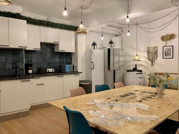 Una cocina moderna con armarios blancos, un salpicadero de azulejos negros y una mesa de comedor de madera con sillas.