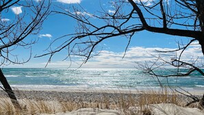 Une plage avec un ciel dégagé, des vagues et des dunes.