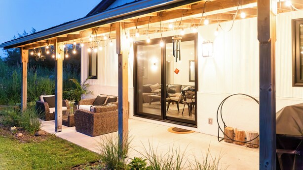 Un espace extérieur aménagé avec des meubles en osier et des guirlandes lumineuses.