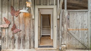 A rustic wooden door with a metal bell and a butterfly decoration. - Charming Serenbe Carriage House (Palmetto)