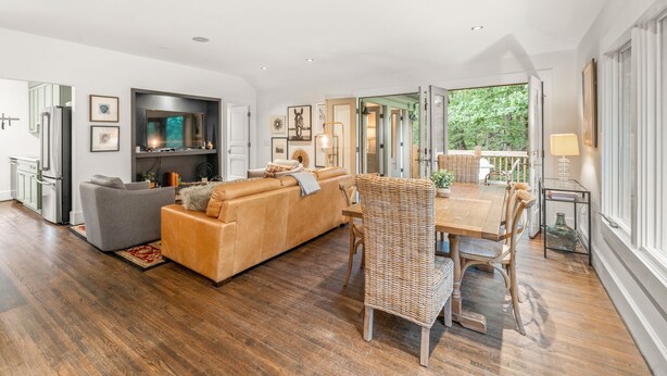 A spacious living area with a sofa, a dining table with chairs, and a fireplace. - Charming Serenbe Carriage House (Palmetto)