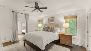 A bedroom with a bed, bedside tables, a ceiling fan, and windows with blinds. - Charming Serenbe Carriage House (Palmetto)