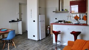A modern kitchen with a refrigerator, stove, and red bar stools. - Lovely apartment for 4 people with A/C, WIFI, balcony and pets allowed (Formia)