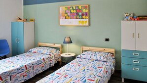A room with two single beds, a small round table, a lamp, and a cabinet with drawers. - Lovely apartment for 4 people with A/C, WIFI, balcony and pets allowed (Formia)