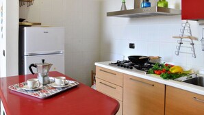 A kitchen with a red countertop, a stove, and various kitchen items. - Lovely apartment for 4 people with A/C, WIFI, balcony and pets allowed (Formia)