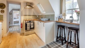 A modern kitchen with a central island, a built-in oven, and a window with a view. - The Old Stables - UK46338 (Canisbay)