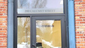 Een bakstenen gebouw met een zwarte deur en een bord waarop staat: Louis Henness Block 1887, 200 Calumet Street.