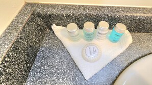 Een granieten aanrecht met een witte handdoek en verschillende flessen Terra Pure douche- en shampoos.