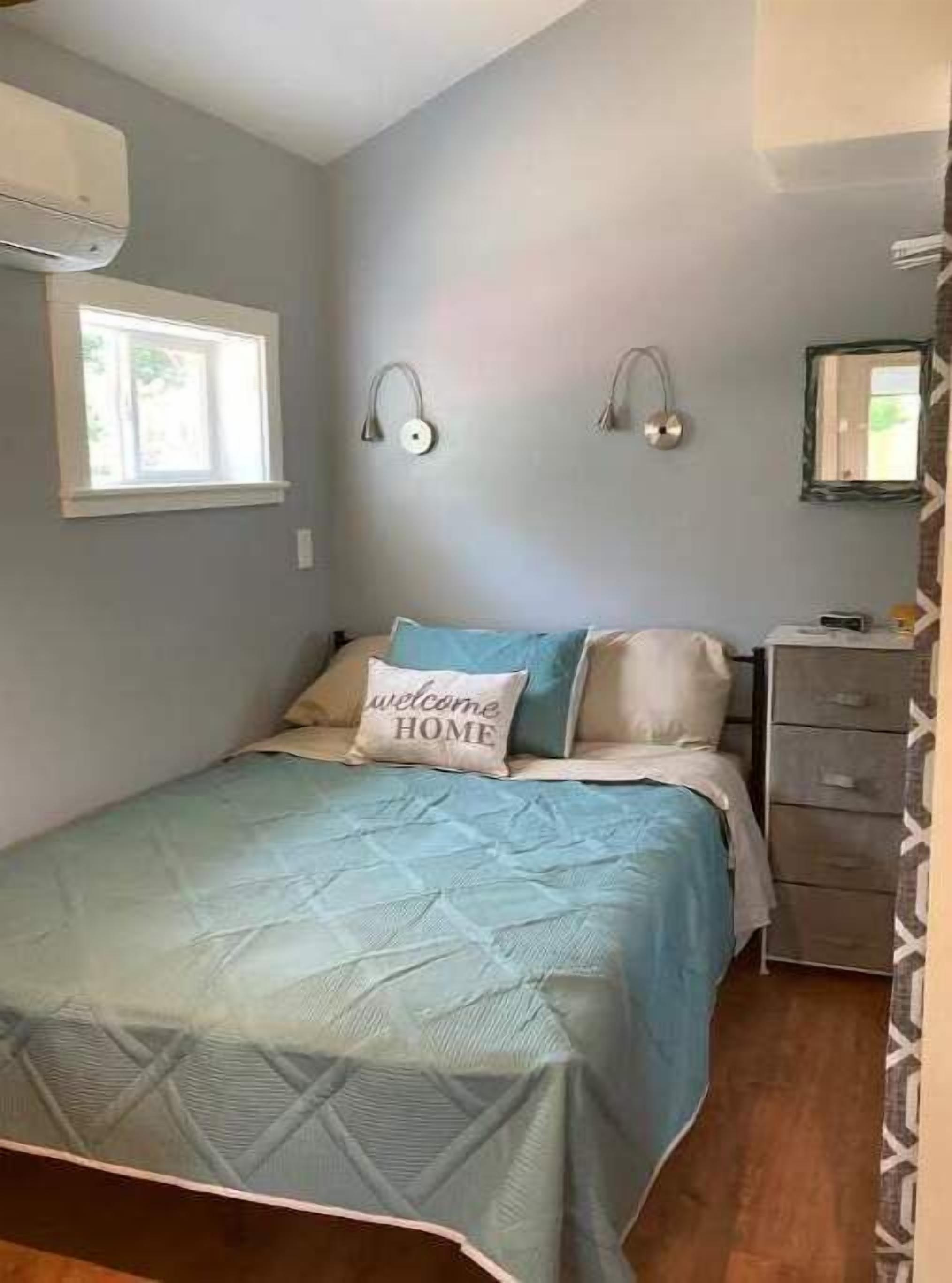 A bedroom with a bed, a dresser, and a window.
