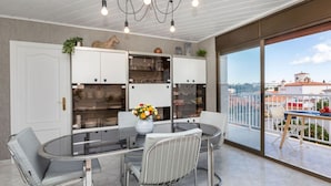 Eine moderne Küche mit weißen Schränken, einem Glastisch und Blick auf die Stadt durch große Fenster.