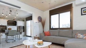 Ein modernes Wohnzimmer mit einer Couch, einem Couchtisch und einem Essbereich mit Stühlen und einem Tisch.