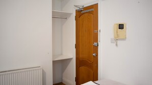 A room with a wooden door, a white radiator, and a telephone on the wall. - Carlton Residence Sleeps 6 (London)
