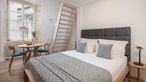 Un dormitorio con cama, escritorio, sillas y una escalera.
