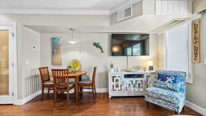 Un comedor con una mesa y sillas de madera, un adorno en la pared y un sillón estampado.