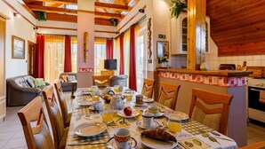 A dining area with a checkered tablecloth, wooden chairs, and breakfast items like croissants and orange juice.