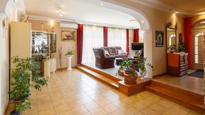 A spacious living room with a sofa, TV, and decorative plants.