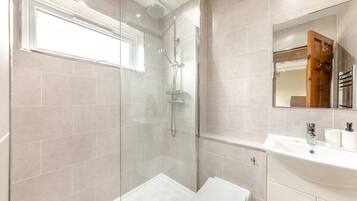 A modern bathroom with a glass-enclosed shower, a white toilet, and a sink with a mirror above it.