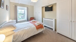 A bedroom with a bed, a chair, a TV, and a wardrobe. - 3 bedroom accommodation in Alnwick (Alnwick)