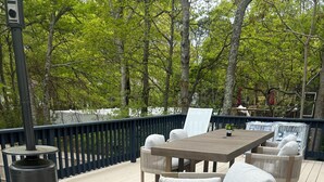 Una terraza de madera con mobiliario exterior, incluyendo sofás y una mesa.