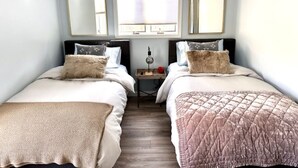 Un dormitorio con dos camas, una mesita y tres espejos.