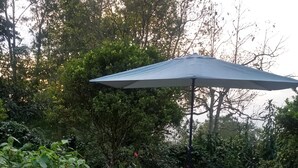 An outdoor patio with a hexagonal tiled floor, surrounded by lush greenery and trees. - Bhakti Coffee Farm (Zipacon)