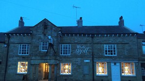A stone building with a sign reading "White Bull" and multiple lit windows. - Ribble Valley Cottage (Preston)