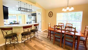A kitchen with a bar area, wooden dining table, and chairs. - Peaceful and Private New House with Hot Tub/ Fire Pit (Spring Hill)