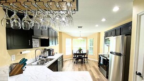 A modern kitchen with a marble countertop, stainless steel appliances, and a wine rack. - Peaceful and Private New House with Hot Tub/ Fire Pit (Spring Hill)