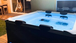 A hot tub with a wooden deck and a glass door leading to an outdoor area. - Peaceful and Private New House with Hot Tub/ Fire Pit (Spring Hill)